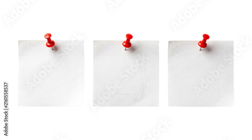 Three white square sticky notes attached with red push pins for office task reminders.