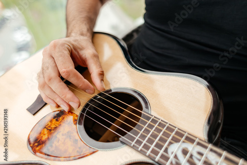 Man play acoustic guitar on balcony during leisure time