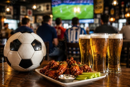 Soccer ball with beer and chicken wings in sports bar