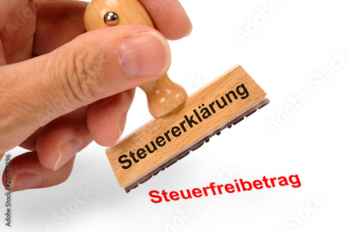 Eine Hand hält einen Holzstempel mit dem Aufdruck Steuererklärung und dem Abdruck Steuerfreibetrag