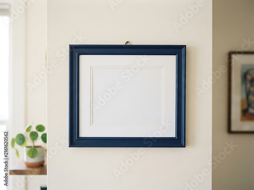 Empty blue picture frame hanging on a white wall for interior design mockup