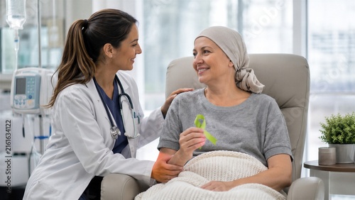 Woman doctor supporting smiling female lymphoma patient holding a green awareness ribbon during cancer treatment
