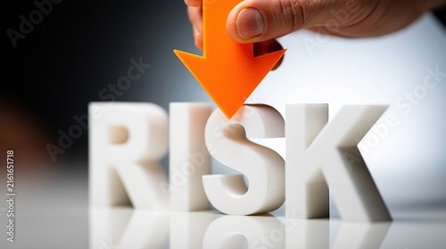 Human hand holding orange arrow pointing down at white risk letters