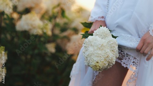 Foto Bride in white dress holding a bouquet of white flowers outdoors