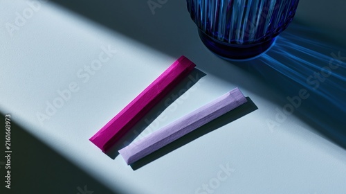 Vibrant pink and light purple paper sticks resting on smooth surface
