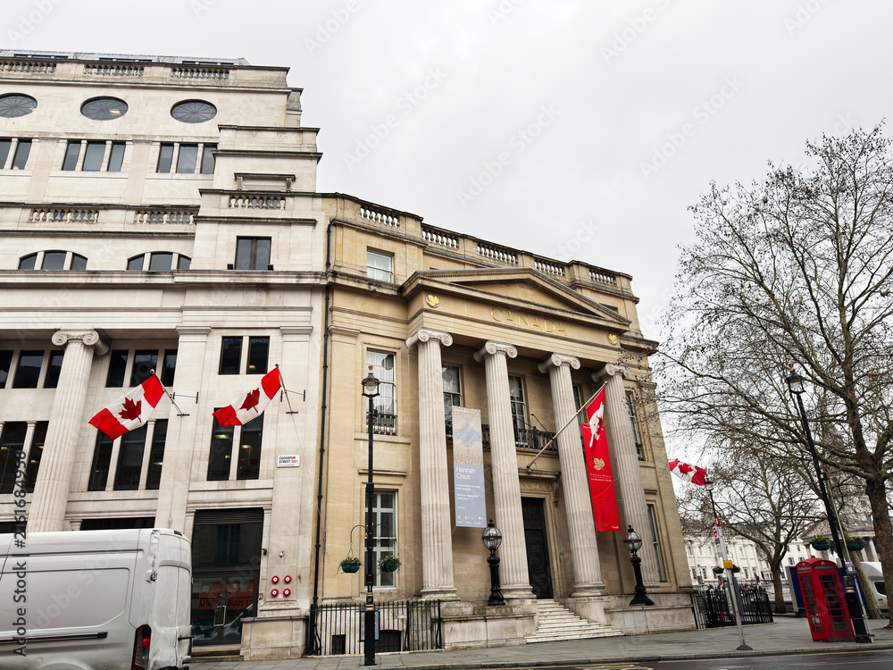 Naklejka premium Historic Canada building with flags and neoclassical columns in central London, UK on overcast day