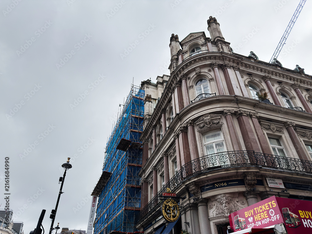 Fototapeta premium Historic Victorian corner building with scaffolding and signage in Spring Gardens, London, UK on overcast day