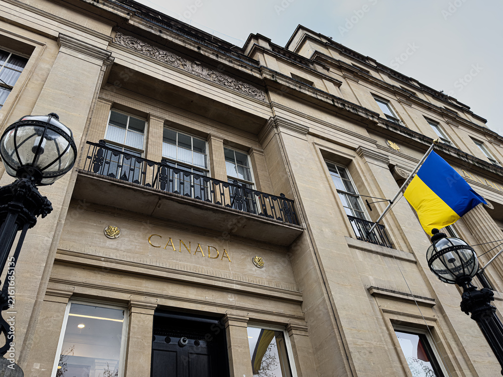 Naklejka premium Canada embassy building facade with ukrainian flag and lamps in London, UK photographed from below