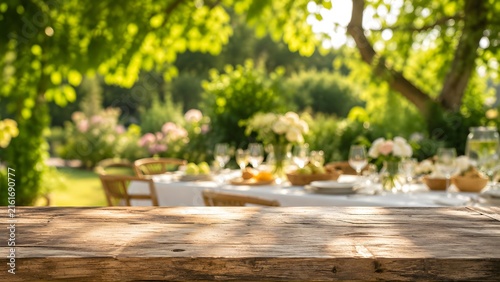Empty wooden table with blurred background of an outdoor dining setting in a lush green garden.