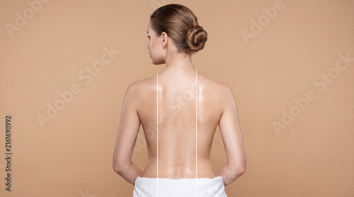 Woman's bare back with glowing skin and towel during studio lighting for wellness advertising