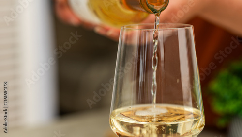 White wine pouring into elegant tasting glass