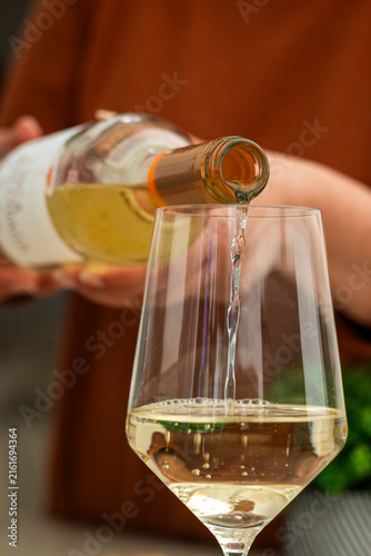 Close up of pouring white wine into glass at home