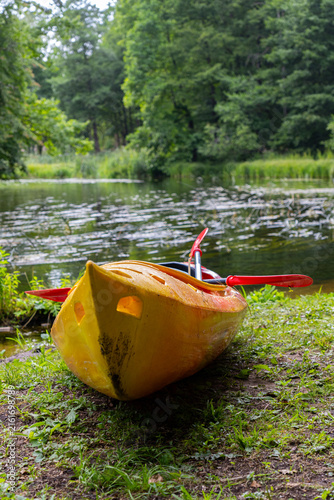 Canvastavla Colorful yellow and orange kayak with paddles beside a forest stream, outdoor wa