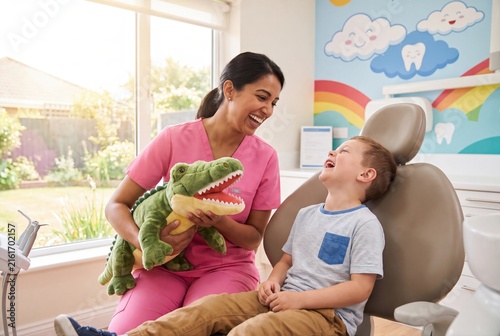 Pediatric dentist and happy child laughing with toy crocodile in clinic
