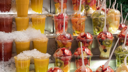 Fresh cut fruit cups with kiwi and strawberry at a market stall, close-up healthy snack display — concept: healthy eating, grab-and-go snacks, fresh fruit market, street food nutrition