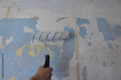 Foto Hand Holding Paint Roller Painting Peeling Wall During DIY Home Renovation and W