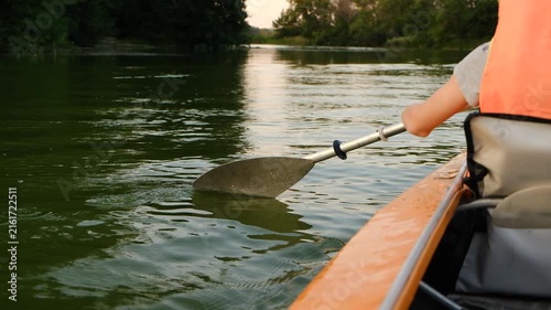 Close-up of paddle dipping into water and splashing during kayak row.