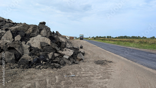 Fotografía Road construction with fresh asphalt pavement and pile of broken asphalt