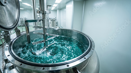 Industrial mixing tank with blue liquid stirred by metal blades with vessel