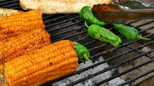 Close-up of seasoned pork belly slices sizzling on hot BBQ grill outdoors with smoke and flames
