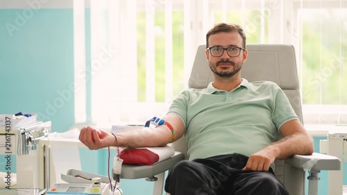 Male blood donor giving blood at donation center