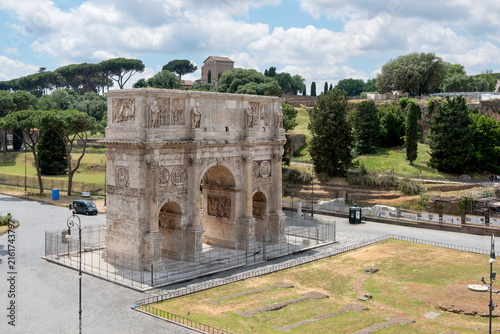 Elevated view of the ancient Arch of Constantine surrounded by green parkland and Palatine Hill under a cloudy sky in Rome, Italy