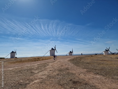Foto Panoramic view of Don Quixote windmills and dirt path under wispy clouds in Camp