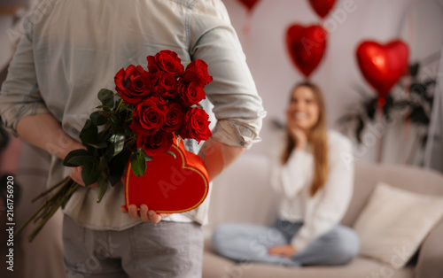 Fotografie Man hiding roses and a heart-shaped gift box for romantic surprise
