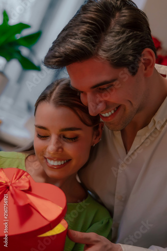 Konstfotografi Smiling couple sharing romantic heart-shaped gift at home