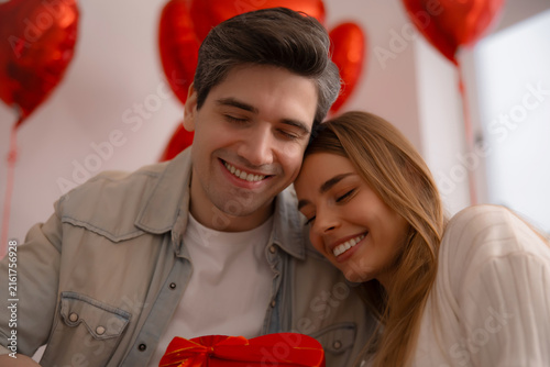 Konstfotografi Affectionate couple cuddling with heart-shaped gift on Valentine's Day