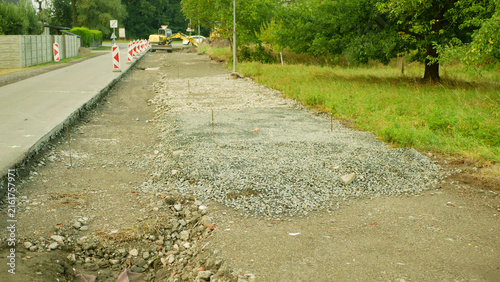 Road construction infrastructure improvement project roadway road widening, sidewalk path construction, drainage improvement, roadway resurfacing, workers installing excavated pathway barriers red