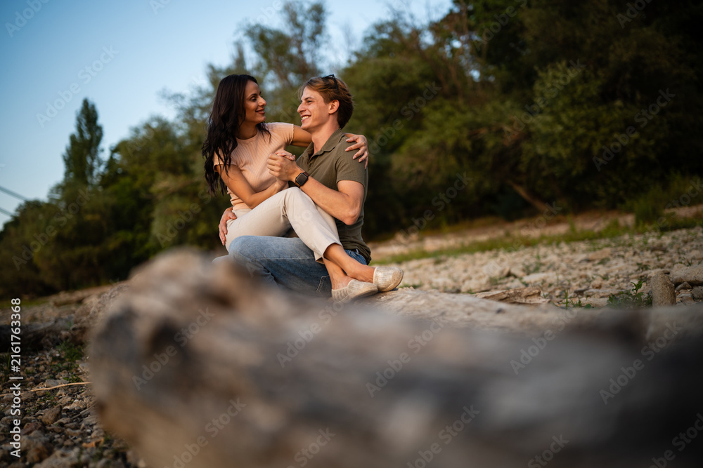 Fototapeta premium Young couple enjoying outdoor date sitting on log