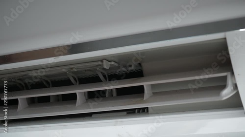 Air conditioner vent and indoor cooling system.
A close-up view shows the open air outlet and adjustable louvers of a wall-mounted split air conditioner with visible dust and internal components.