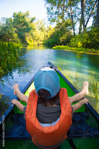Caucasian child boy, 5 years old, with cap and life jacket, sitting on a canoe trip on Tirino River, in Gran Sasso National Park, located in the Abruzzo region in Italy