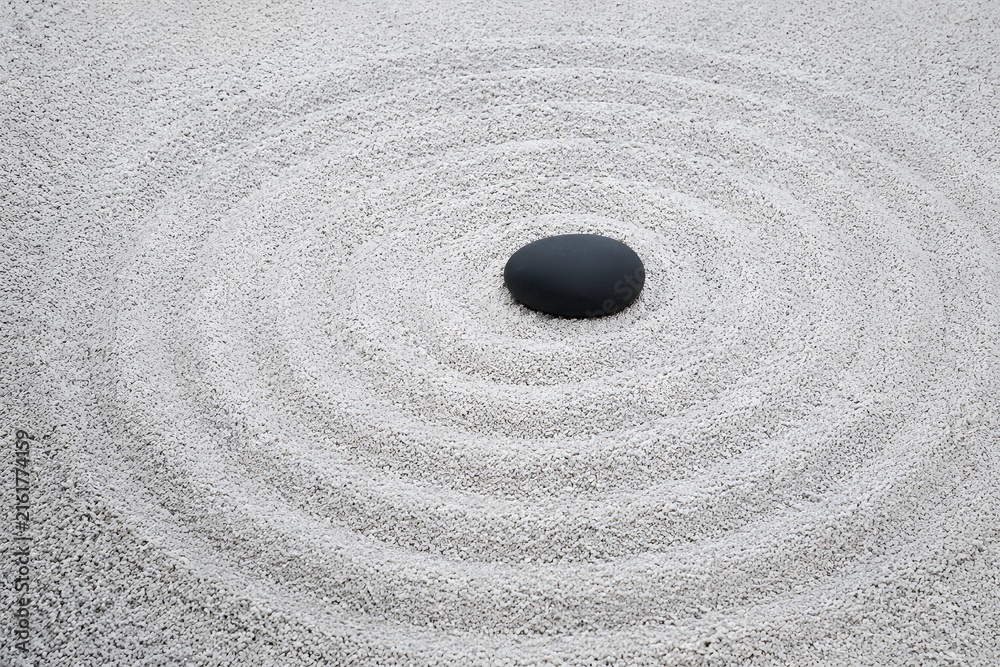 Naklejka premium Zen raked white gravel wave pattern with single smooth black river pebble