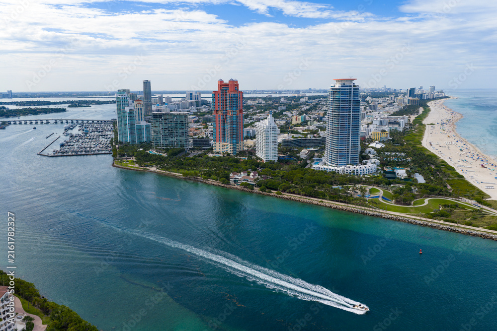 Fototapeta premium Yacht cruising near Miami skyline. Aerial view of boats on turquoise waters in Miami.