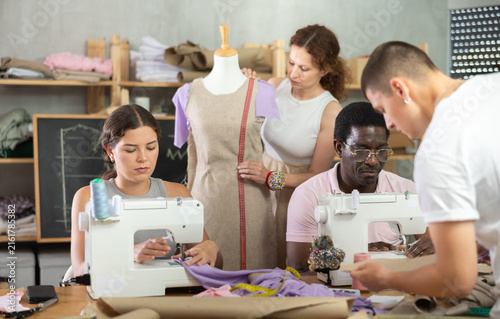 Foto Diverse group of students, women and men, participating dressmaking class, focused on learning practical sewing techniques, constructing and adjusting garments in tailor workshop