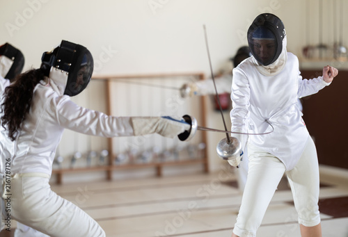 Картината върху платно Man and woman in fencing kit engage in friendly sparring match, focusing on foot