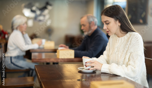 Fotografie Pretty woman drinks coffee in a cafe interior