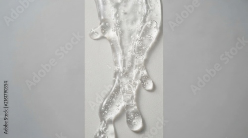 Clear gel dripping against neutral grey background.