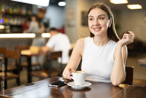 Bild auf Leinwand Pretty woman drinks coffee in a cafe interior