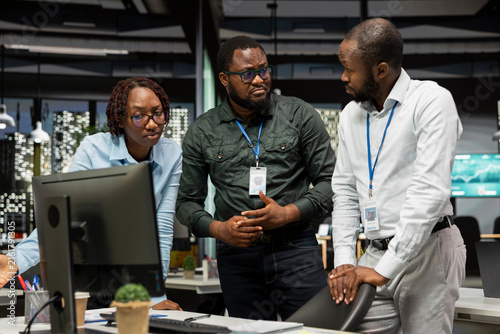 African American employees work late on goal setting while studying data insights and performance metrics and creating reports for business administration with colleagues in a strategy room.