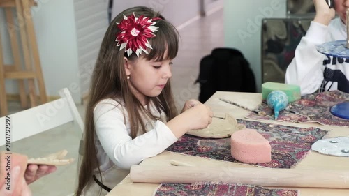Little girl sculpting ceramic craft with clay during art workshop in studio.
