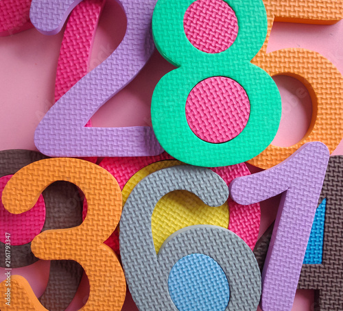 Colorful numbers background. Colorful foam puzzle numbers piled up on a pink background