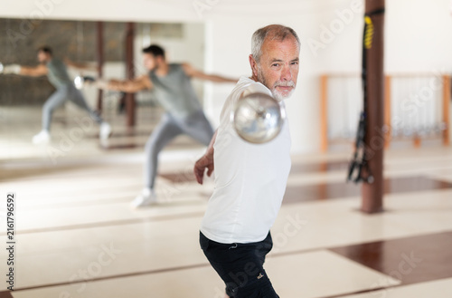 Картината върху платно Elderly male fencer practices footwork and blade movements in sports hall