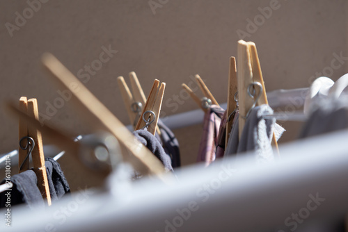 Wooden clothespins hanging on a drying rack with laundry outdoors