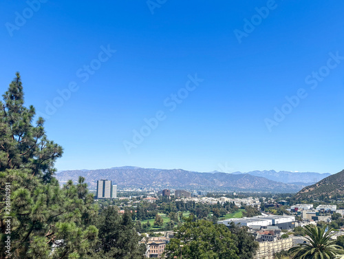 Morning haze over a green valley with distant mountain range and hillside beneath a vast clear blue sky with copy space