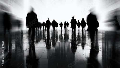 Silhouettes of people walking in a bright, blurred hallway
