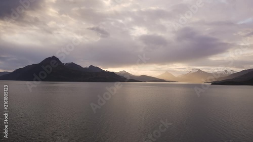 Epic Sunset Wide View in Antarctica. Seen From Cruise Ship. Golden Light Around Mountains in Silhouette. Snow Covered Peaks. Cloudy Sky at Dusk.