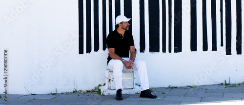 Foto A tall, stylish, dark-haired, thin, 40-year-old white man with a beard is wearing white pants, black shoes, a black polo shirt